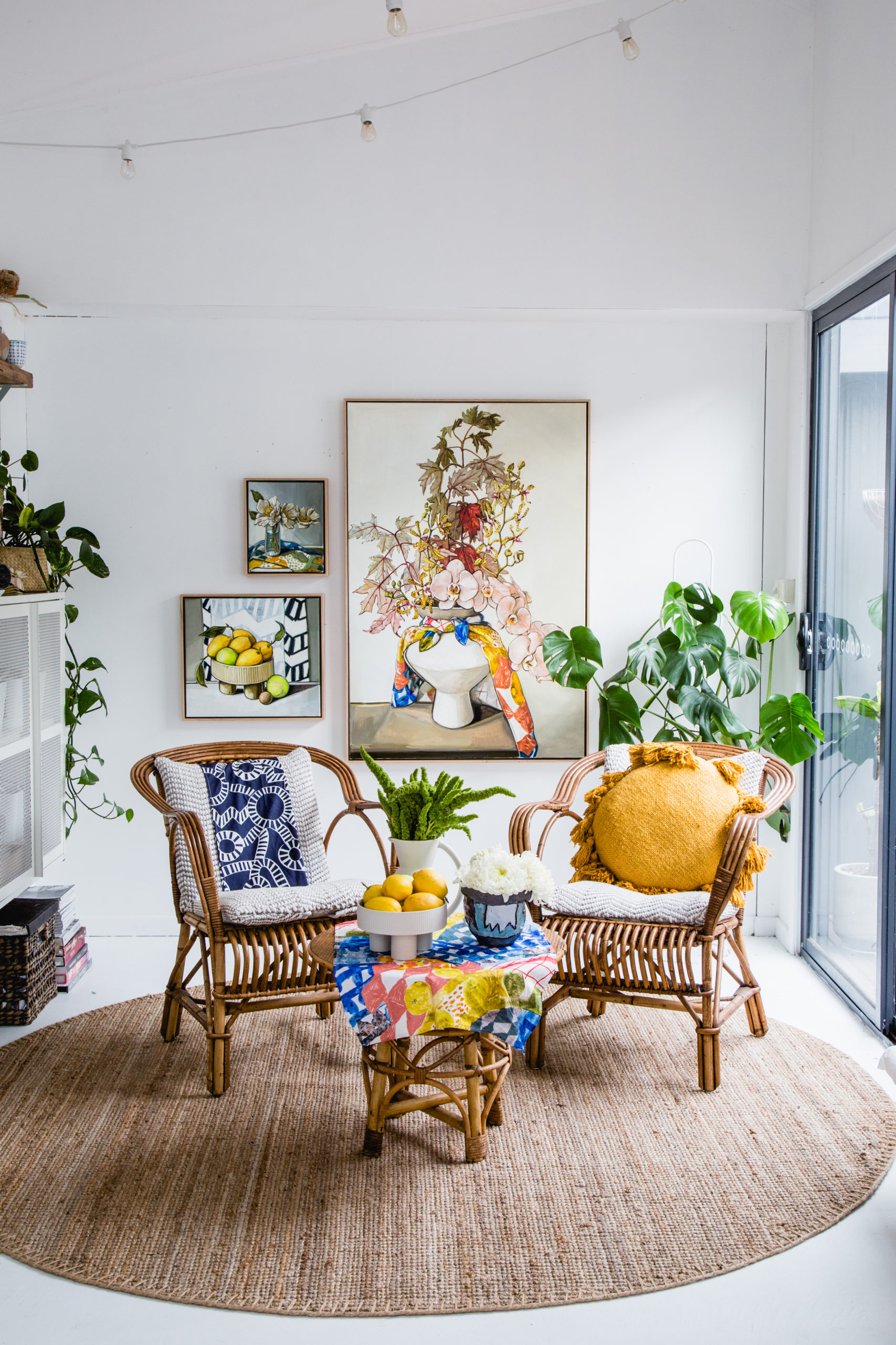 3 paintings of fruit and flowers displayed on the wall of a sitting room.