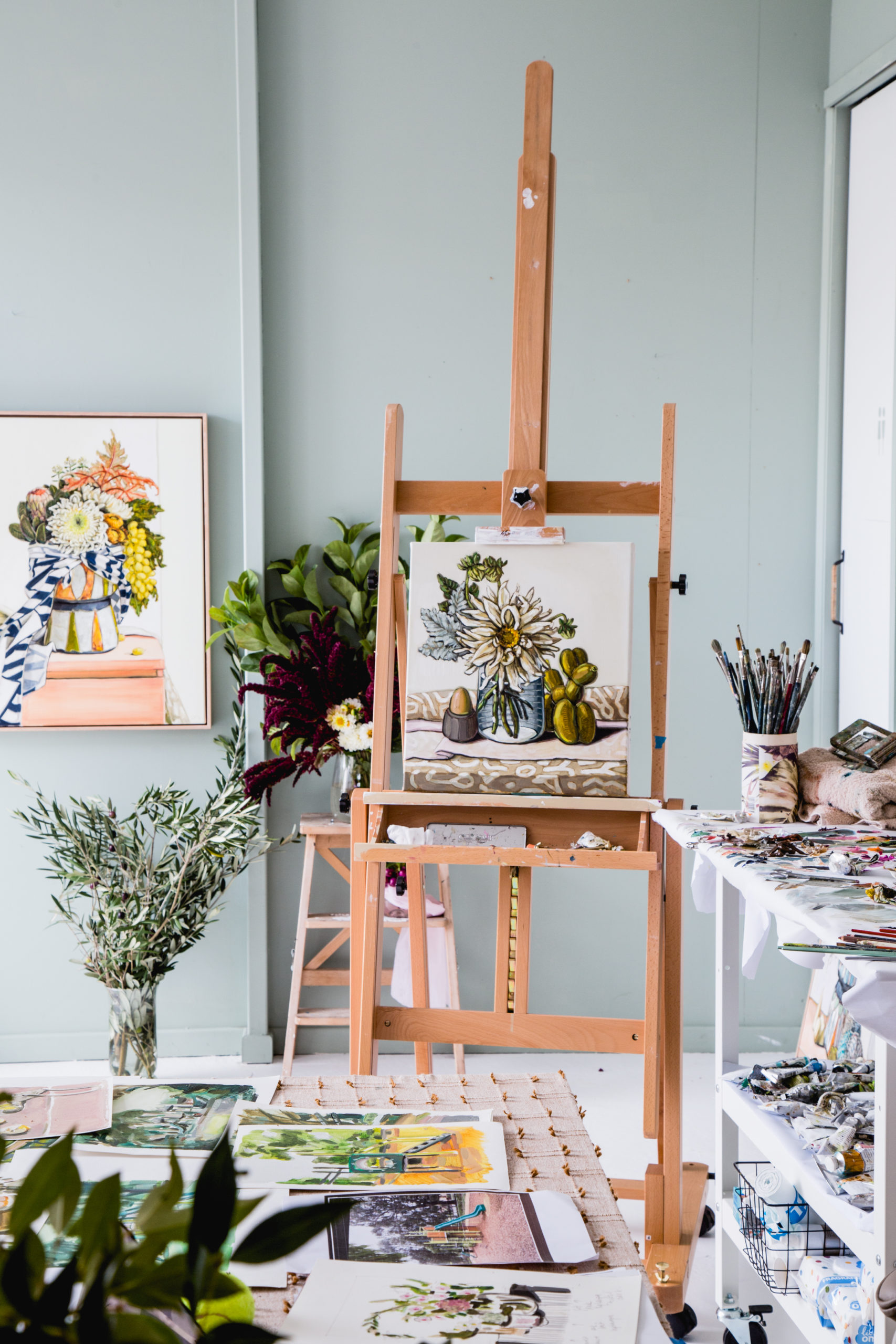 An artist's studio with a painting of flowers on an easel.