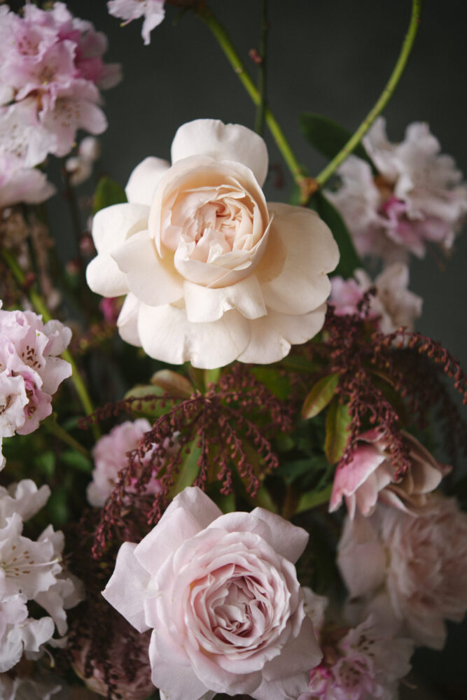 This photograph depicts a few pale pink roses within a floral arrangement.