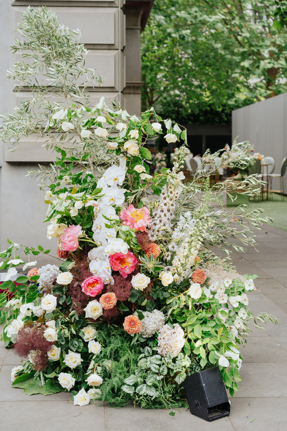 An abundant flower arrangement outside beside a path. The flowers are pink and white.