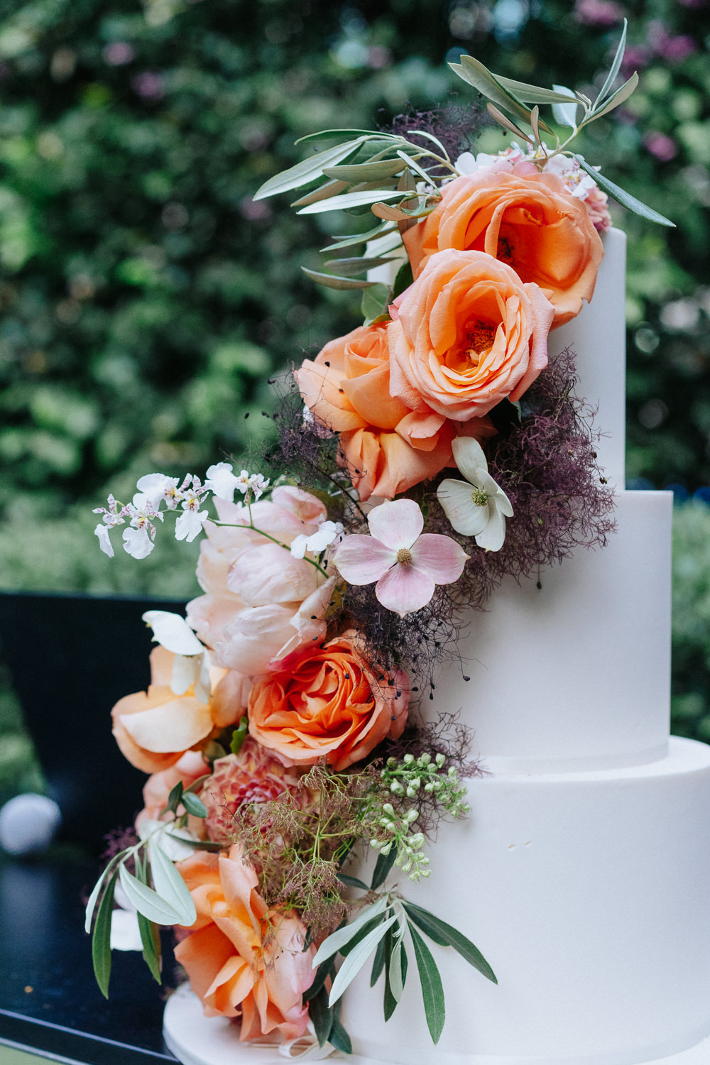 A white wedding cake decorated with pale orange roses.