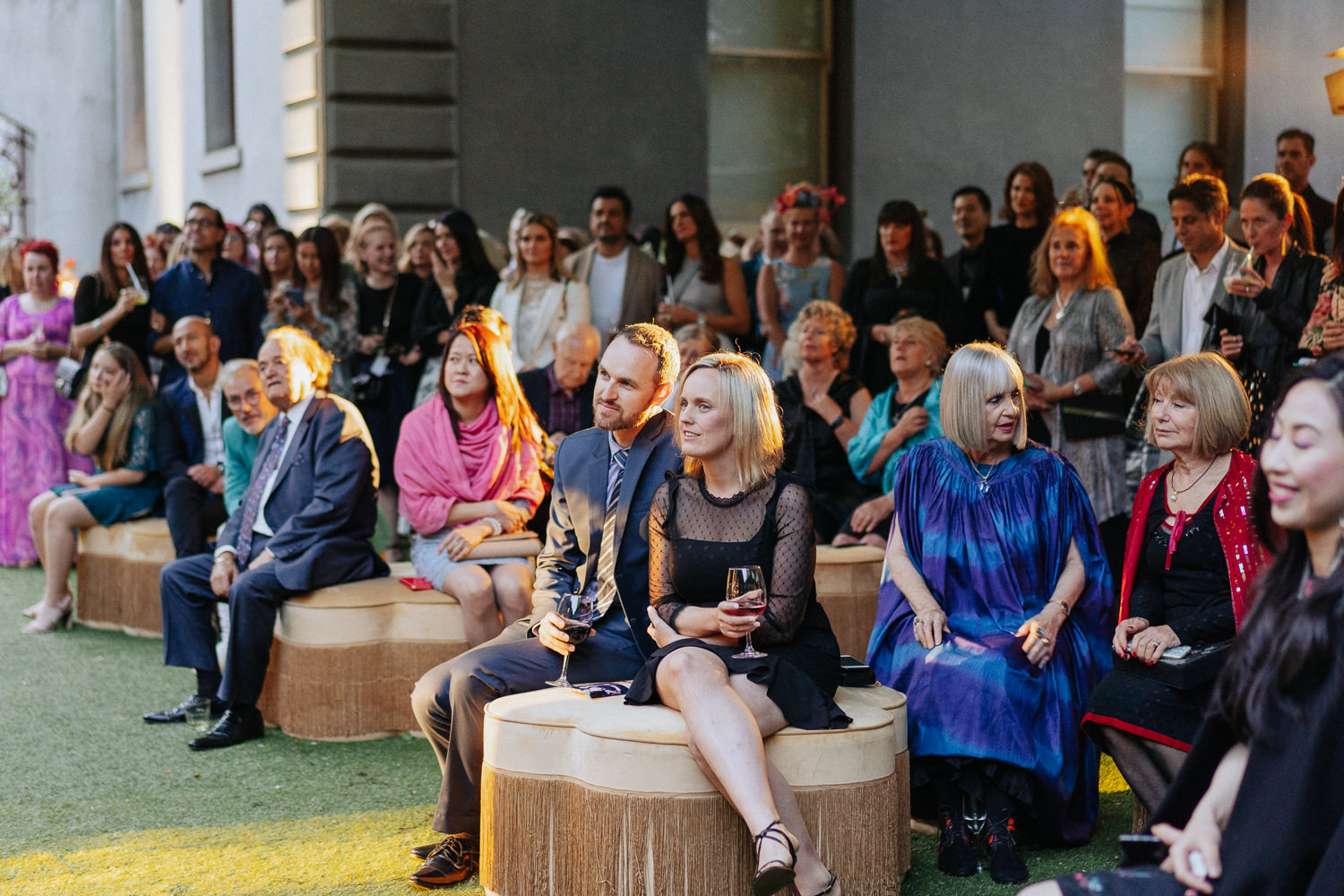 A group of people at an outdoor event, they are all facing a speaker.