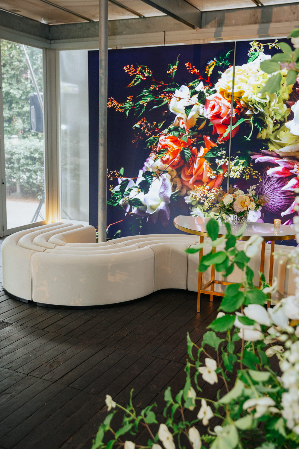 An event space with a large photograph of flowers on a screen. A small arrangement of flowers is on the table in front of the screen.