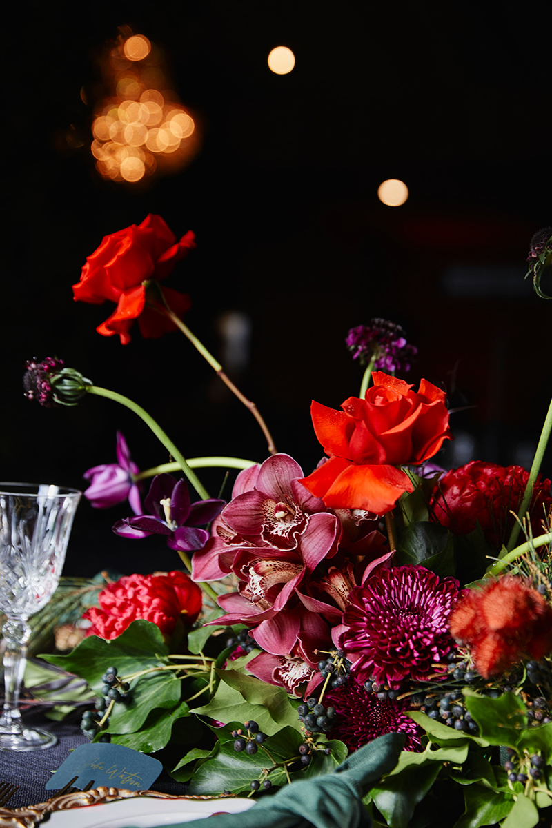 A purple and red floral arrangement on a dining table.
